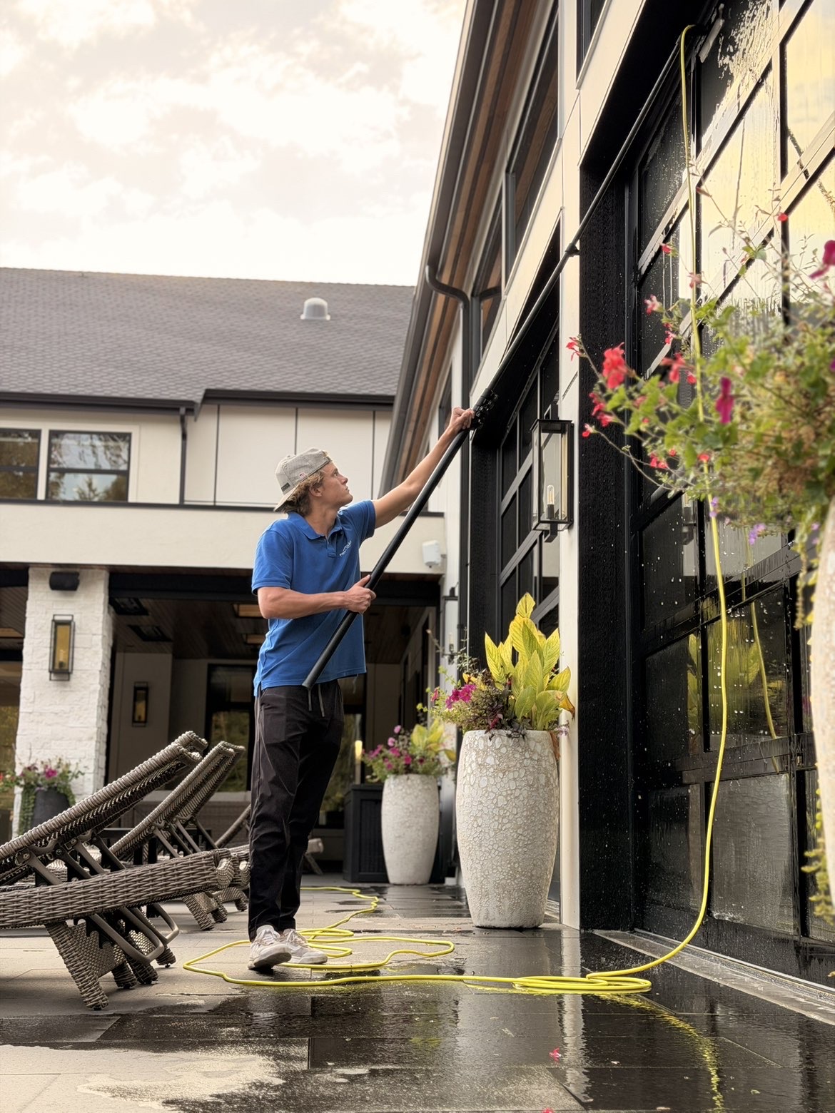 First Class Window Cleaning crew member cleaning second-story windows with a water-fed pole